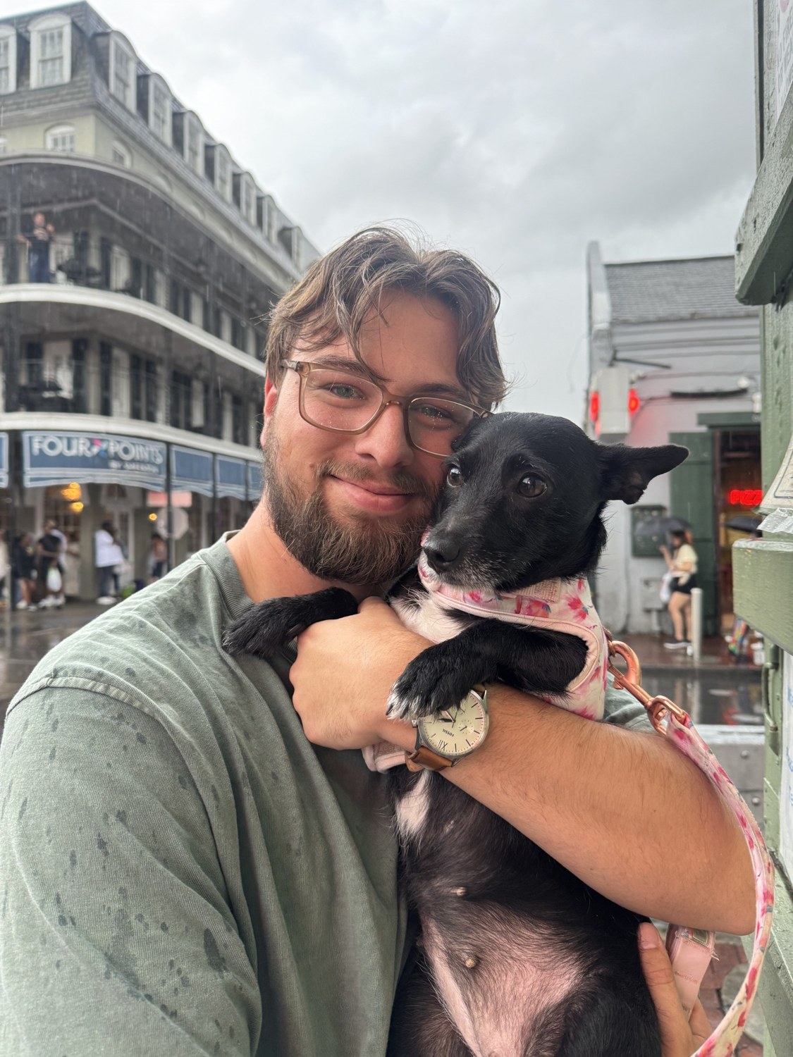 Justin holding Gleppy, his small black dog, outdoors.