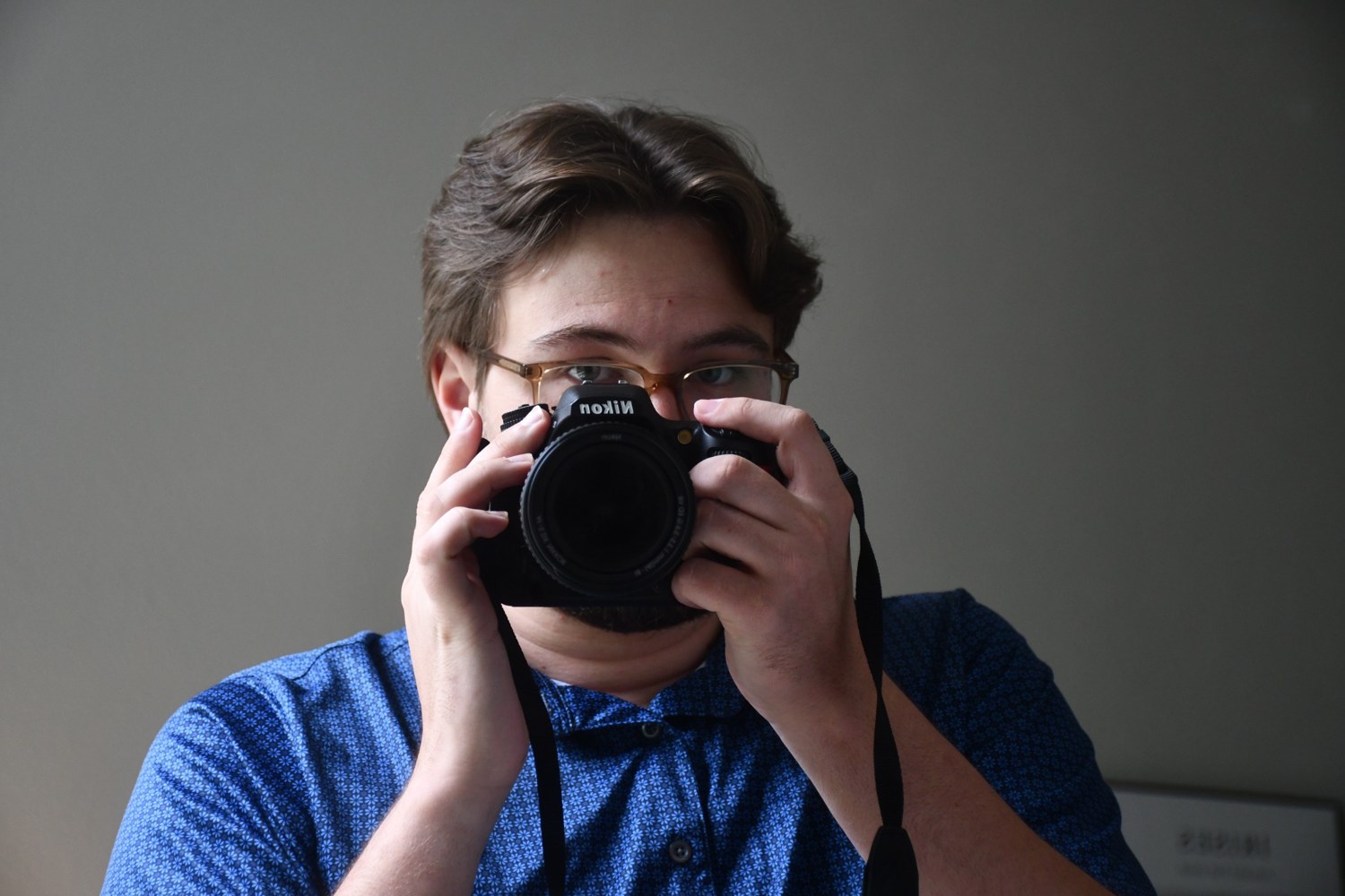 Justin Glowacki holding a Nikon camera up to his face.